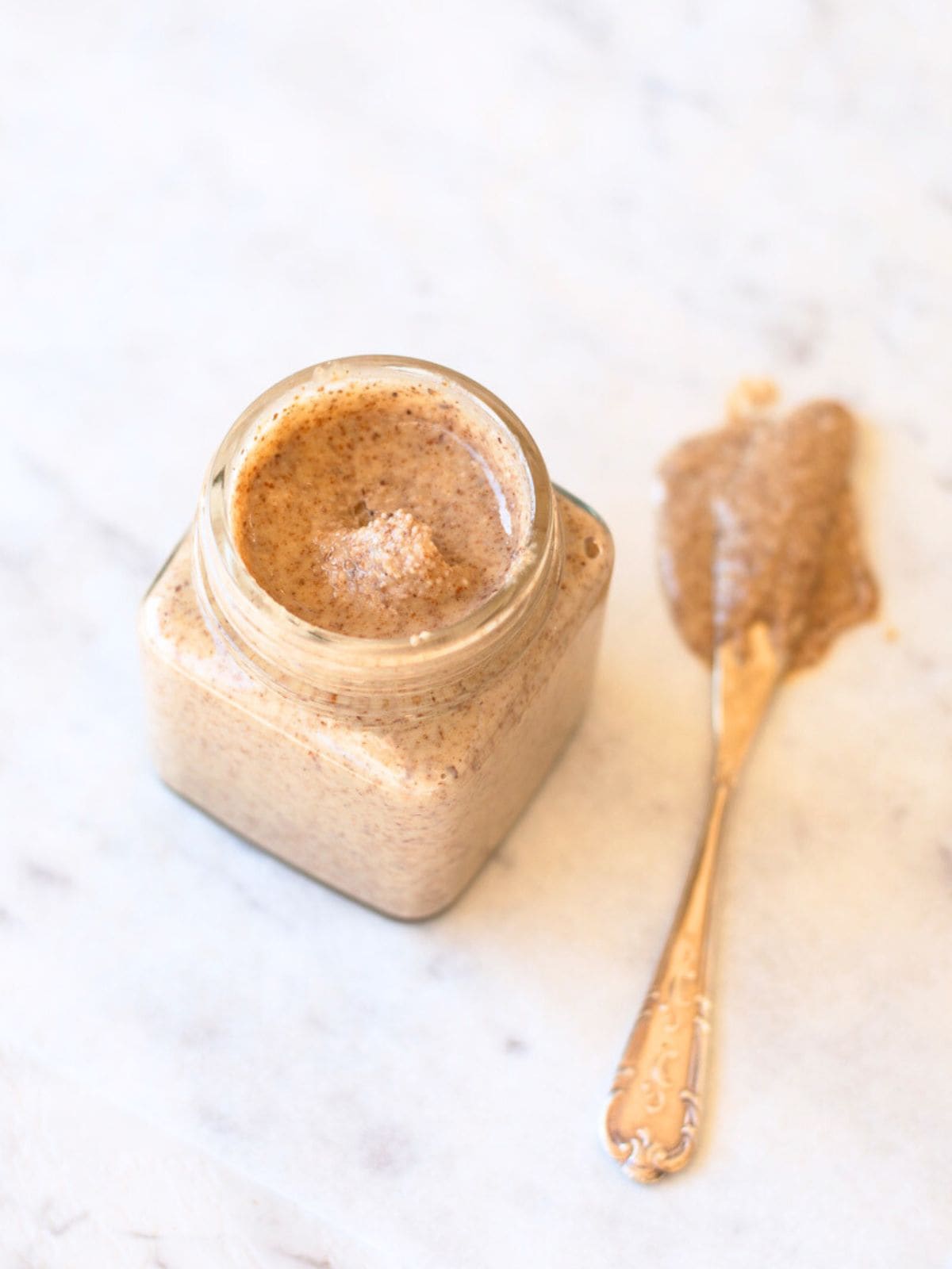 Image of homemade almond butter in a glass jar with a knife.