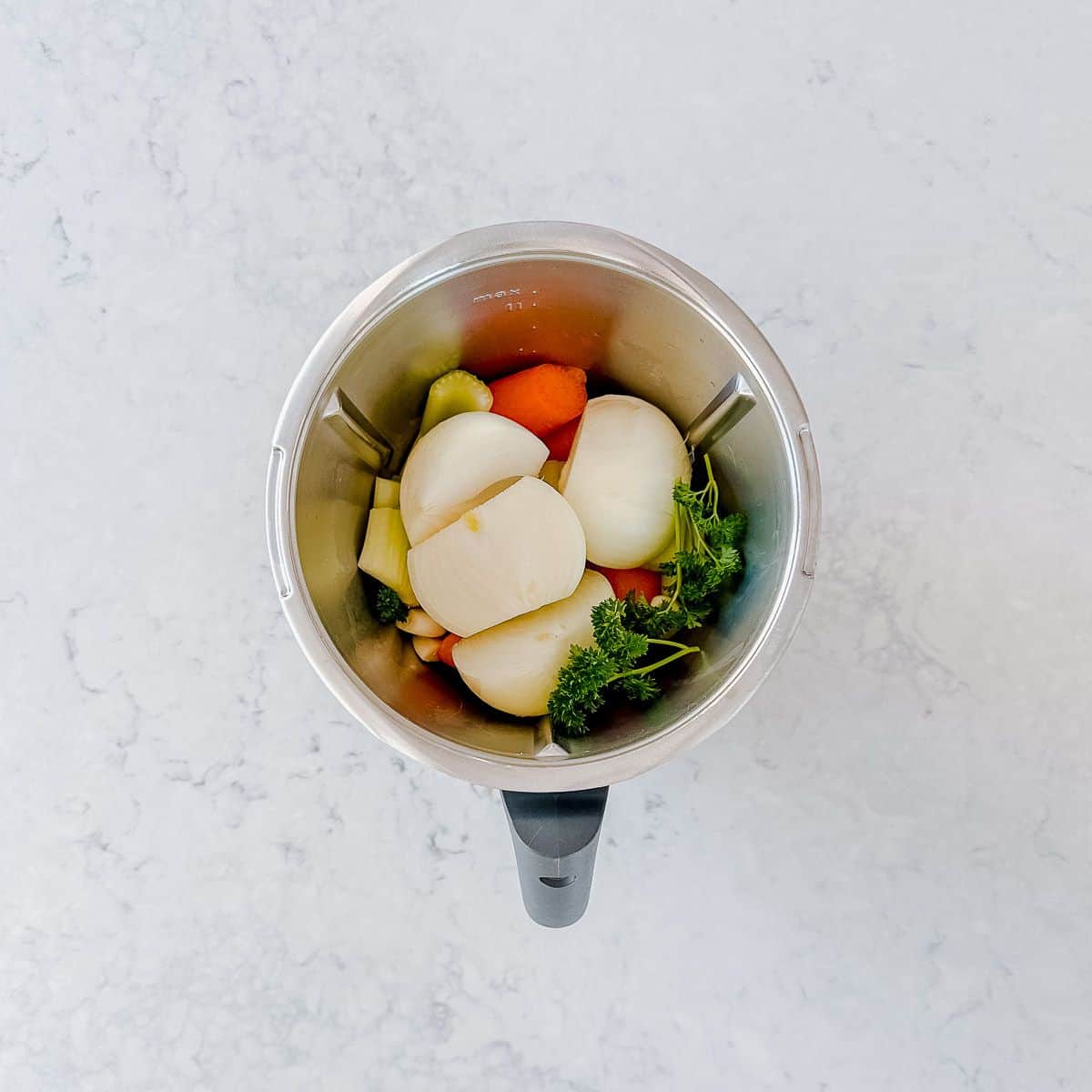 Onions, parsley, carrots and celery in a Thermomix bowl.