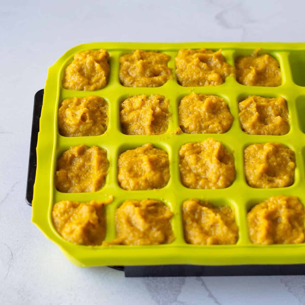 Vegetable stock concentrate in a lime green ice cube tray.