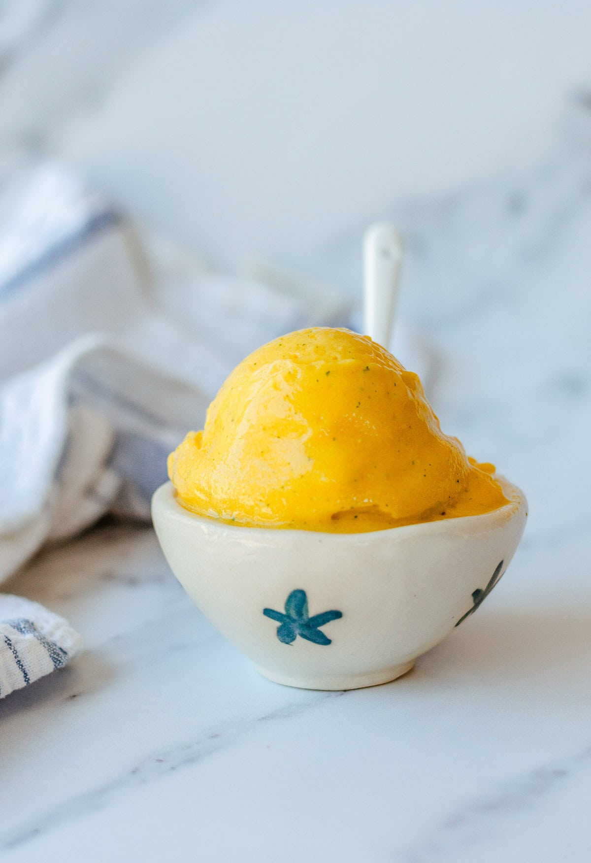 mango sorbet in a cream bowl with white spoon.