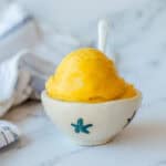 Mango Sorbet in a white bowl with white spoon.