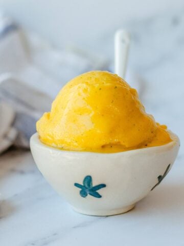 Mango Sorbet in a white bowl with white spoon.