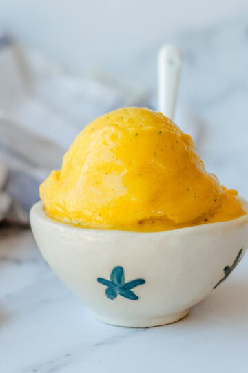 Mango Sorbet in a white bowl with white spoon.