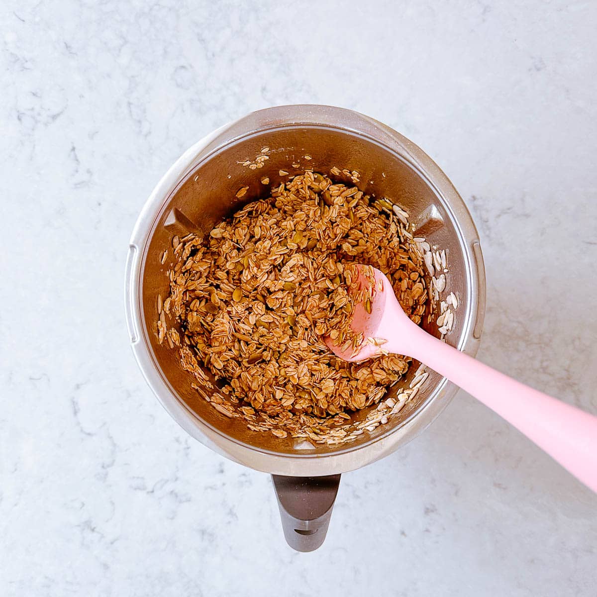 Homemade granola in a Thermomix bowl with pink spatula.