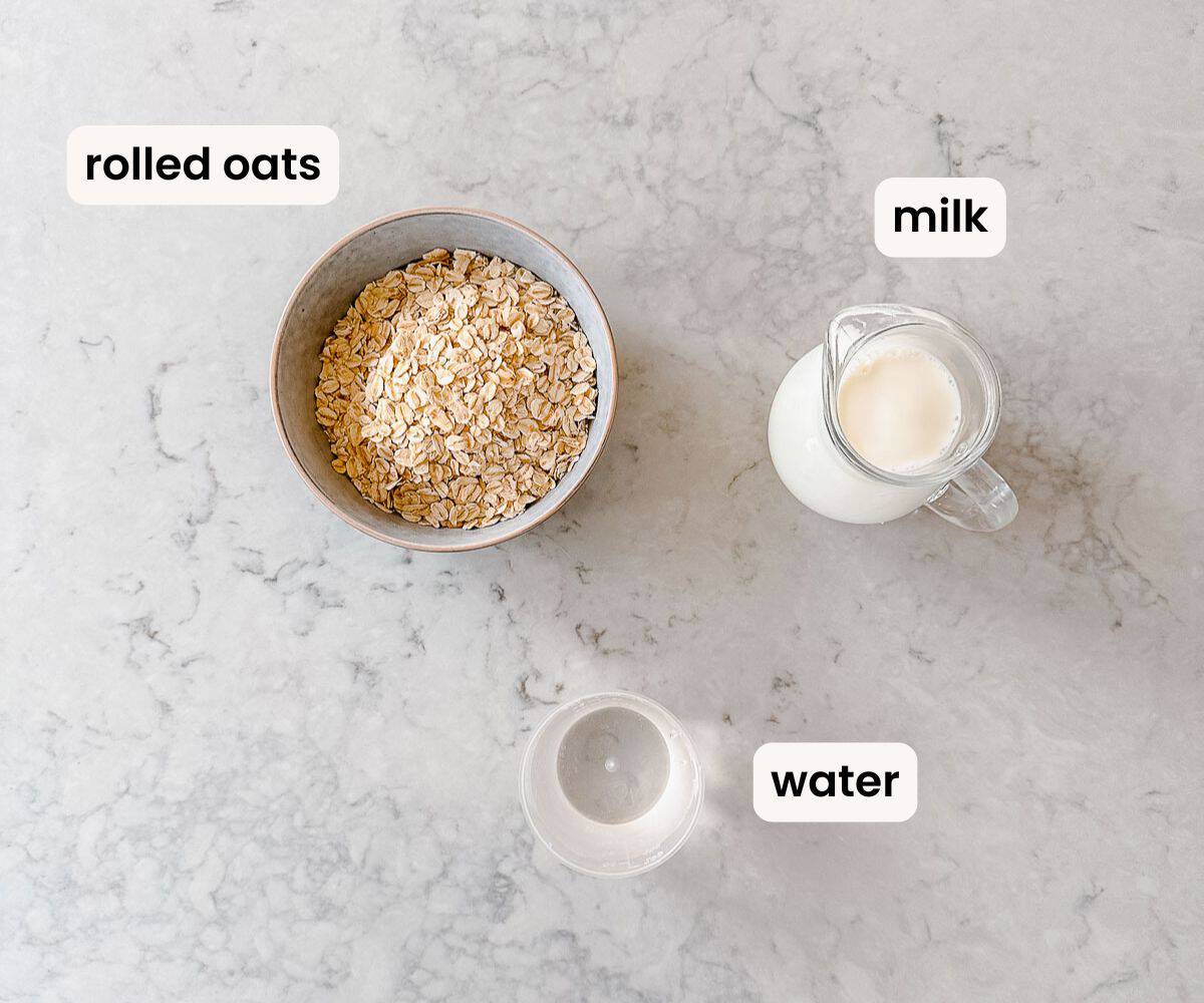 a bowl of rolled oats, a jug of milk, and bowl of water sitting on a marble benchtop, all labeled.
