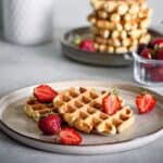 Waffles on a grey plate with strawberries.