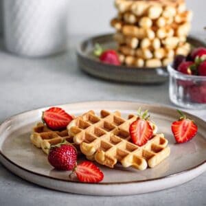 Waffles on a grey plate with strawberries.