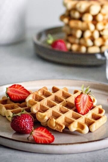 Waffles on a grey plate with strawberries.