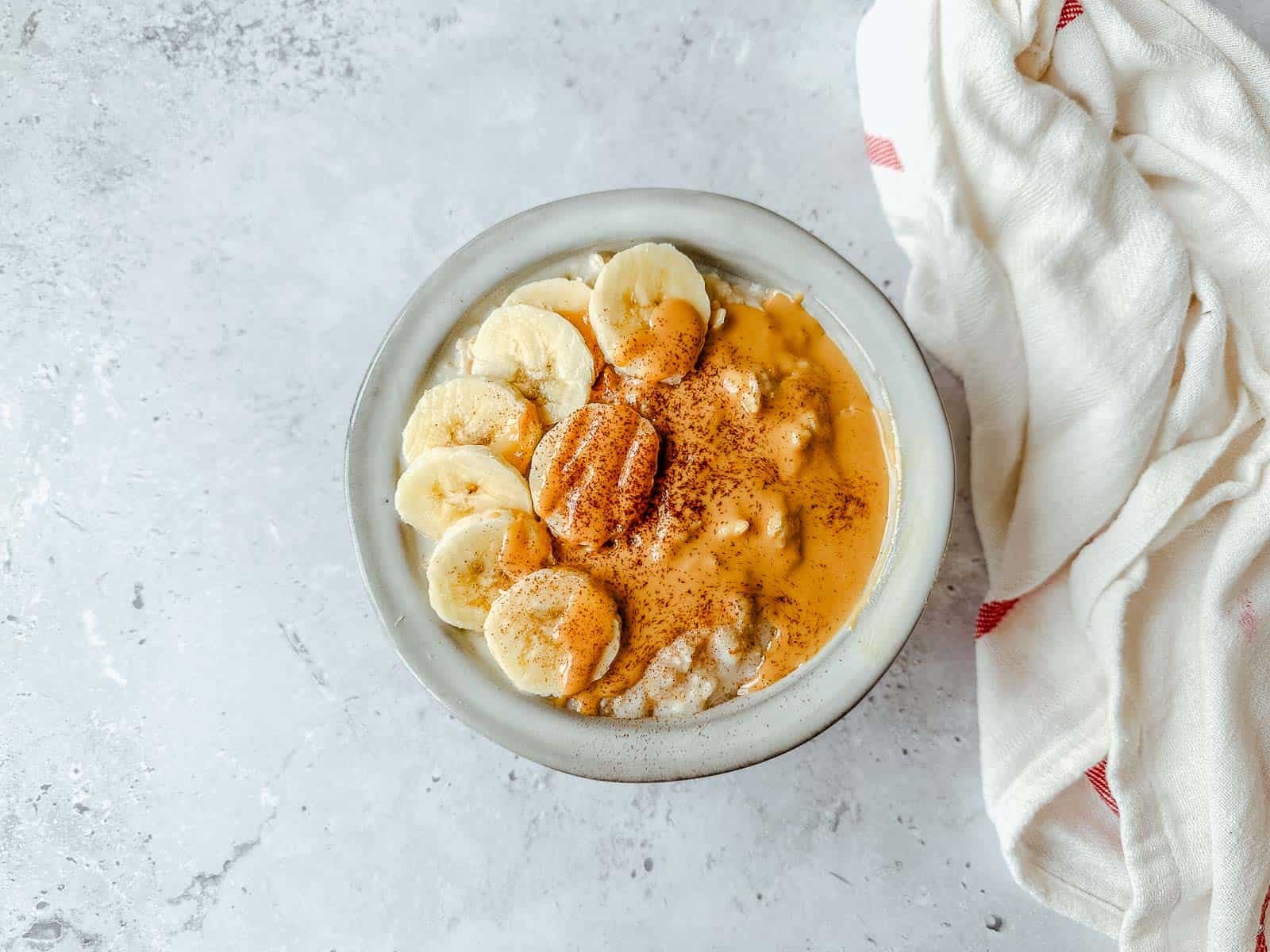 Porridge topped with sliced banana, peanut butter and cinnamon.