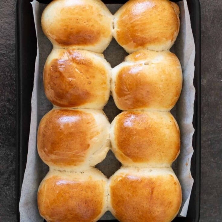 8 round bread rolls on a baking tray.