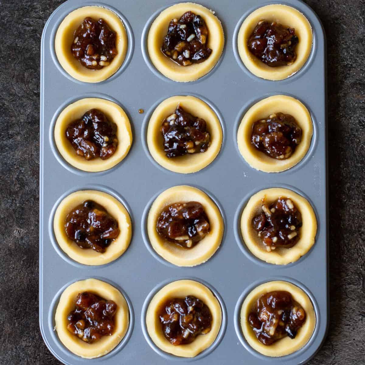 pastry rounds in a patty tin filled with mincemeat
