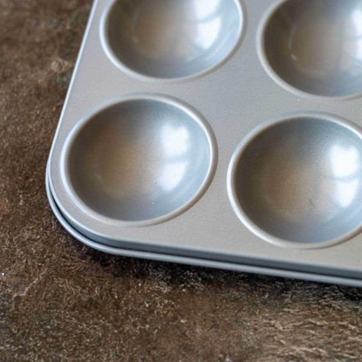 A grey patty tin on a brown background.