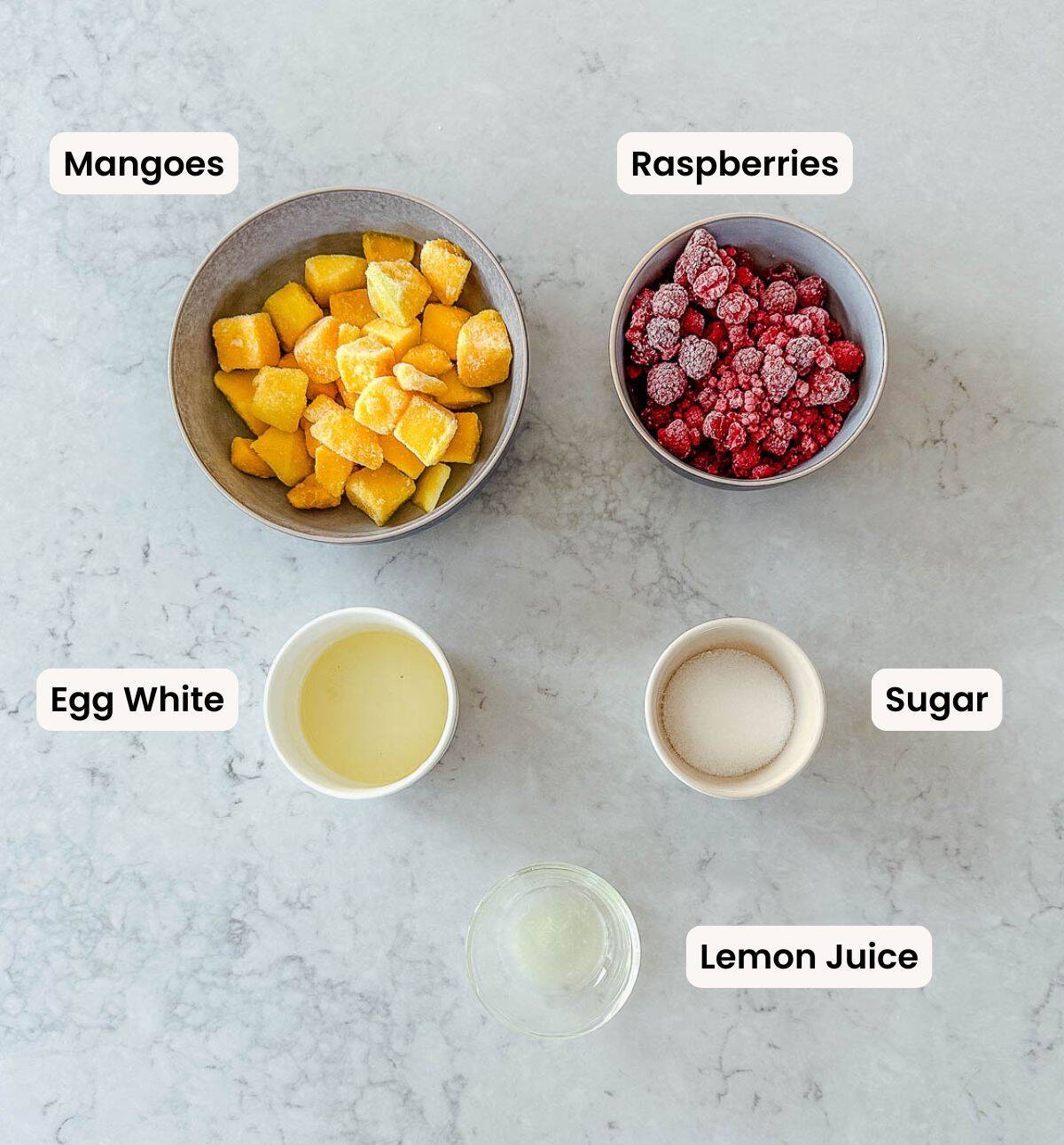 A collection of ingredients needed to make raspberry mango sorbet.