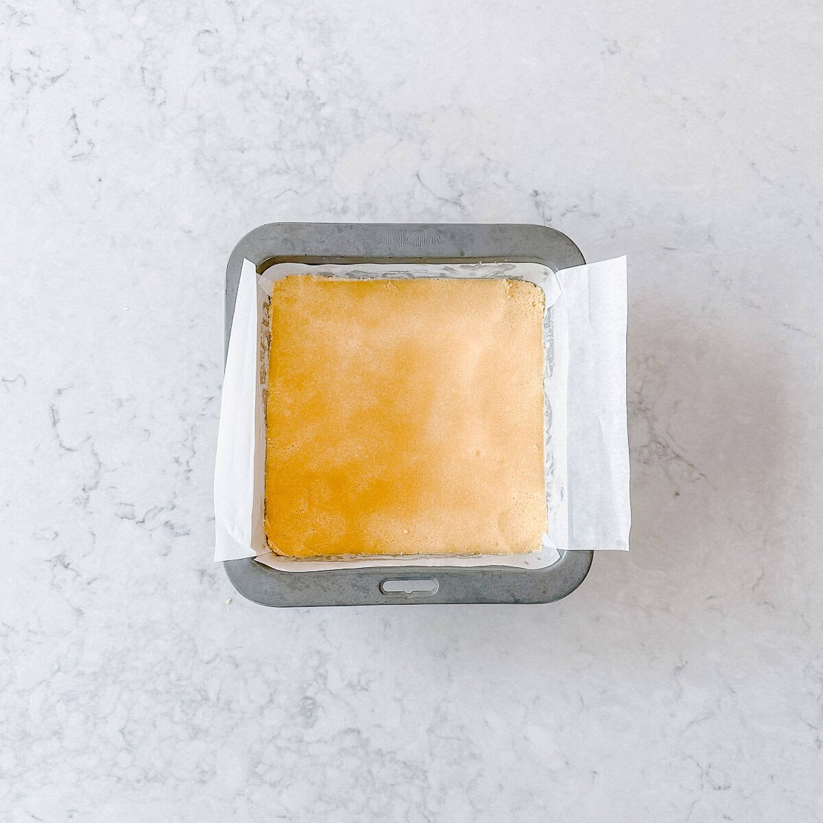 Raw shortbread mixture in a square tin.