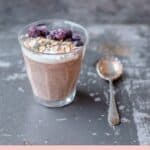 Chocolate Chia Pudding in a glass jar with yogurt, seeds and berries on top.
