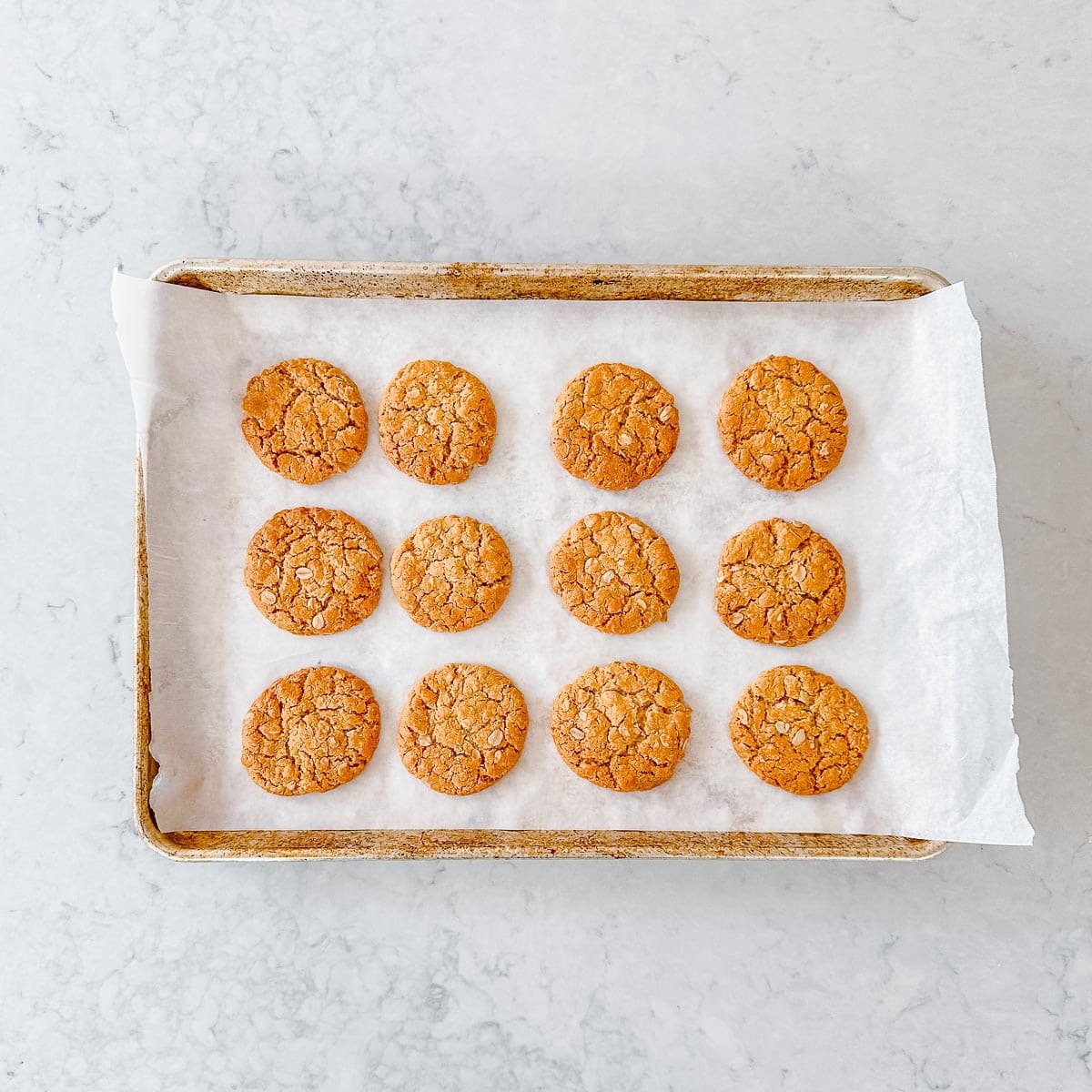 Baked Anzac biscuits on a baking tray.
