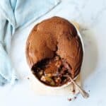 Chocolate Pear Pudding in an oval dish on a marble bench top, with blue tea towel on the side.