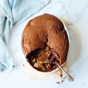Chocolate Pear Pudding in an oval dish on a marble bench top, with blue tea towel on the side.