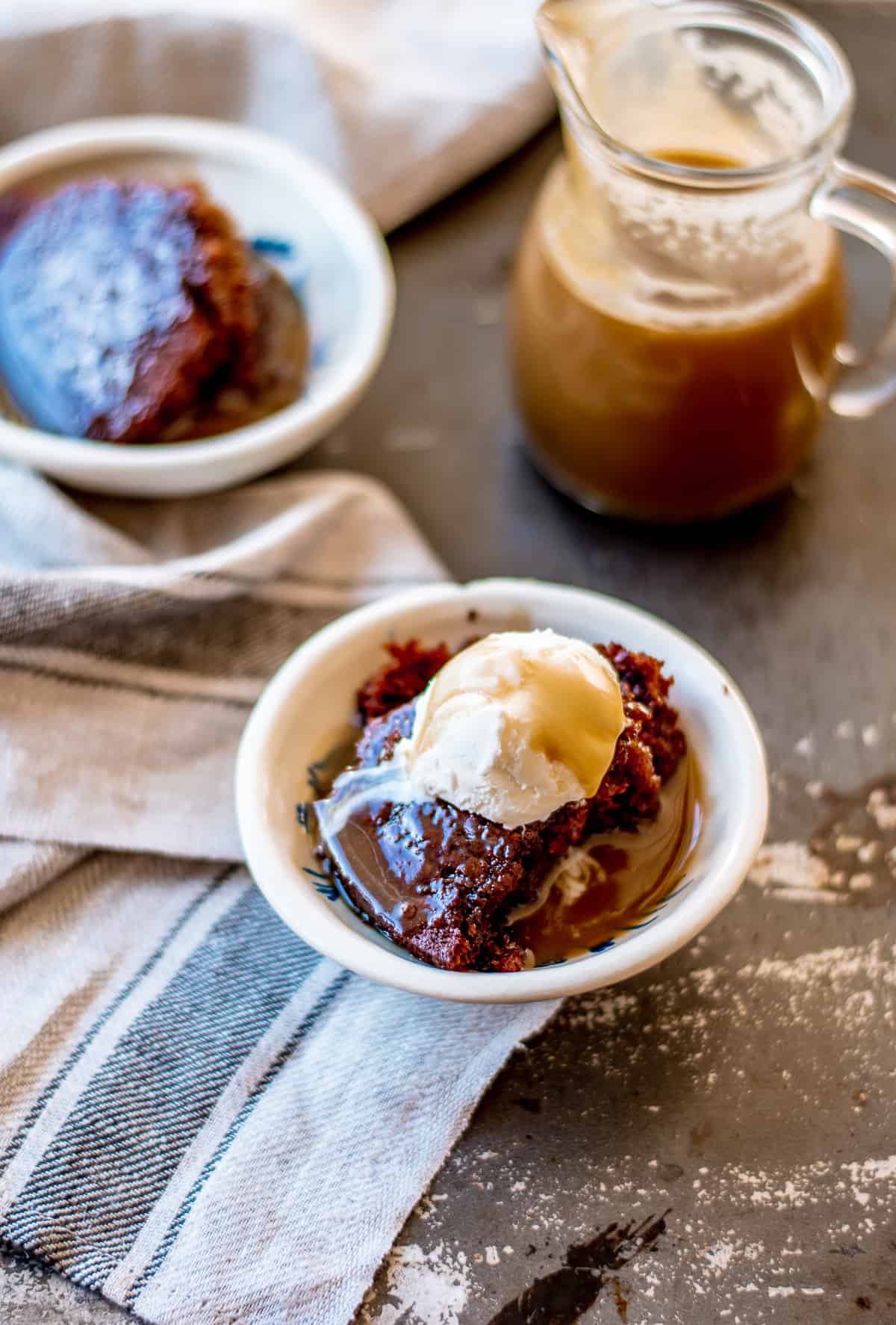 Sticky date pudding with butterscotch sauce and iceream in a bowl.