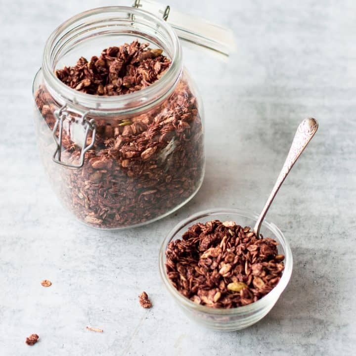 Homemade Chocolate Granola in a glass bowl and jar with silver spoon