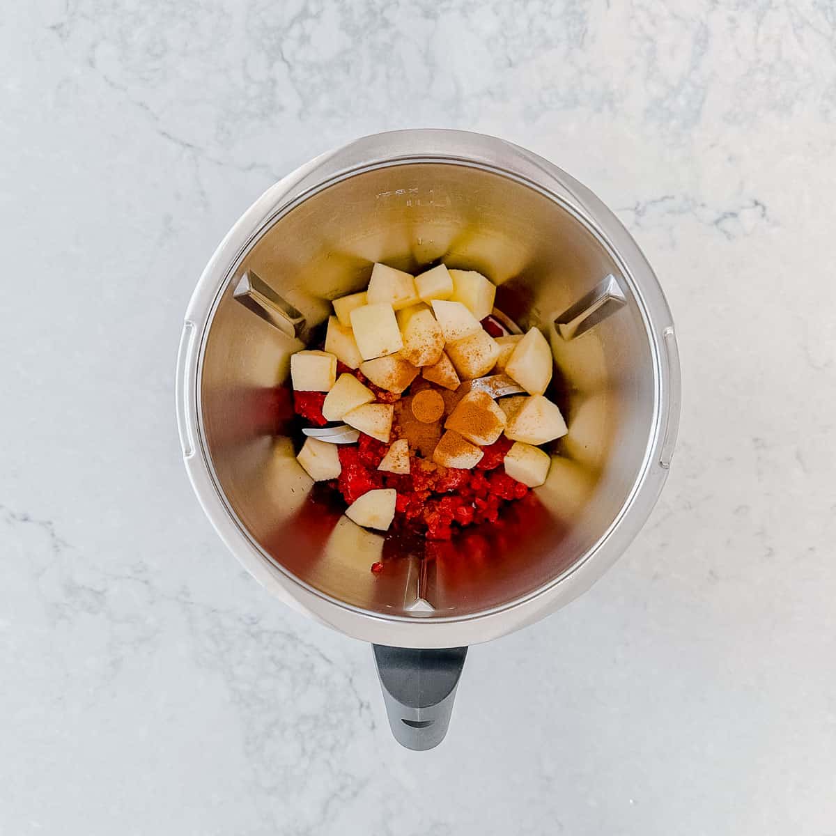 Apples and raspberries in a thermomix bowl.