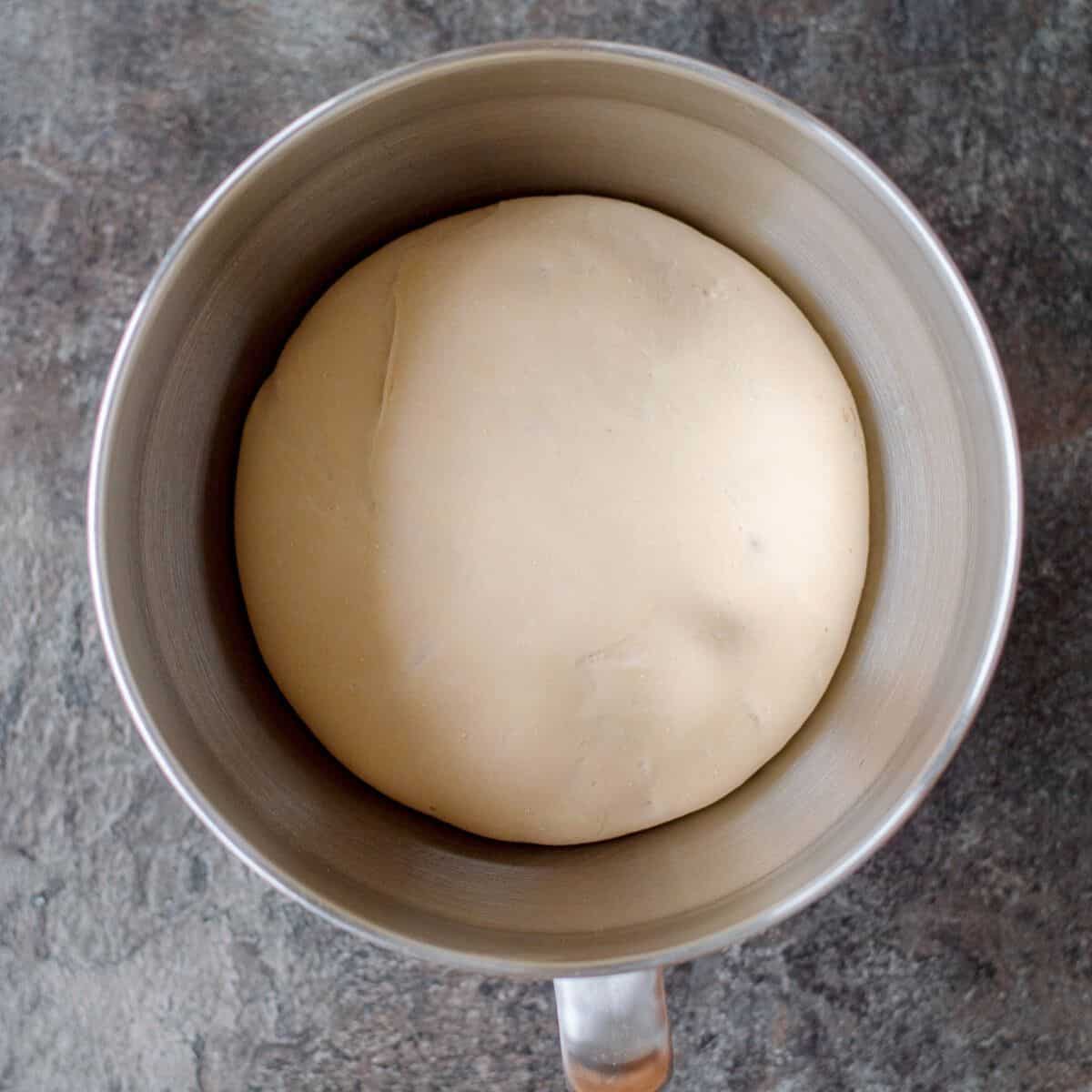 Dough risen in a large metal mixing bowl.