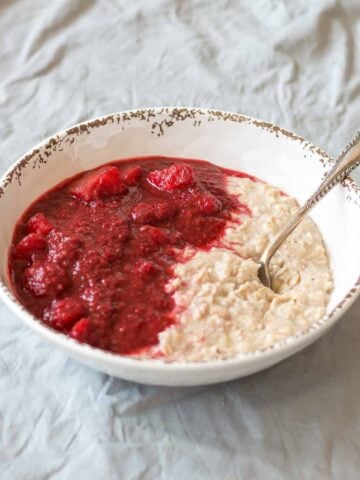 Apple and Rasberry Compote with porridge in a white bowl
