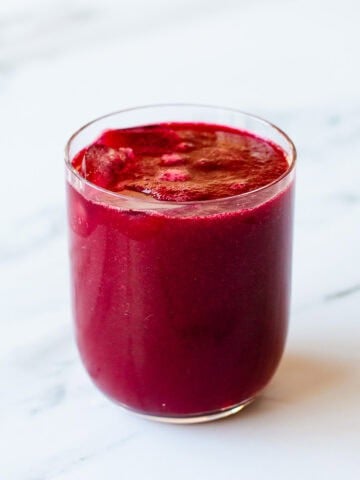 Beetroot juice sitting on a marble kitchen benchtop.