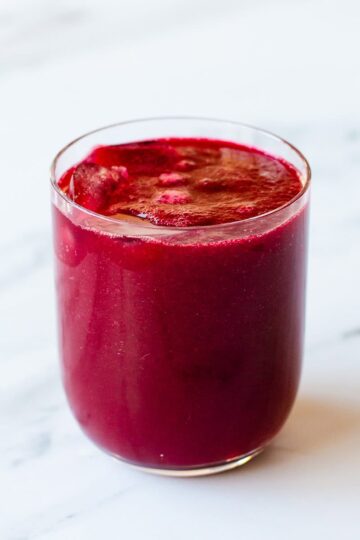 Beetroot juice sitting on a marble kitchen benchtop.