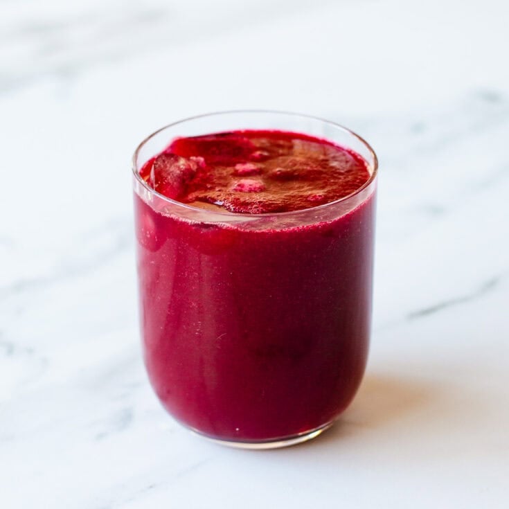 Beetroot juice sitting on a marble kitchen benchtop.