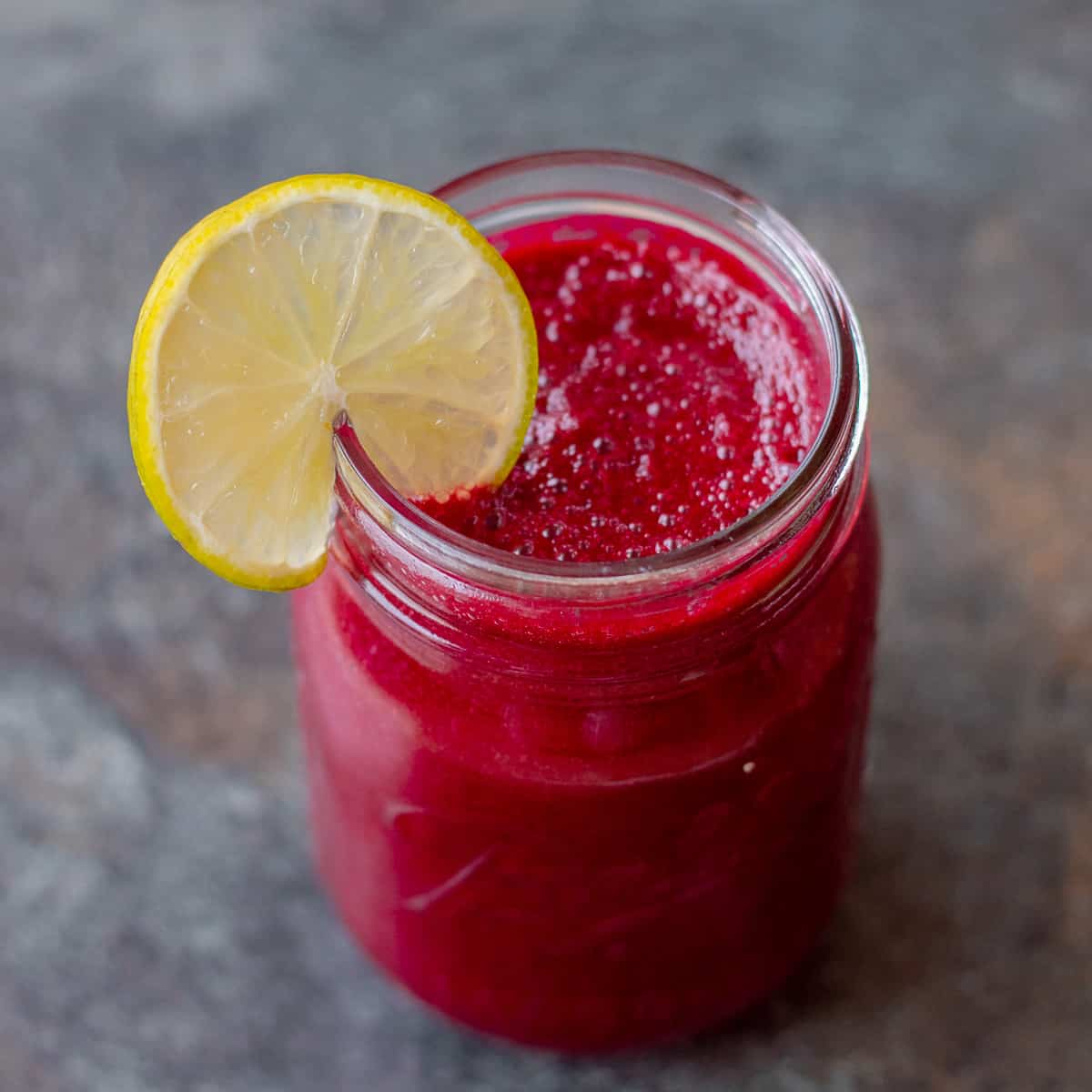 Beetroot Carrot and Pear Juice in glass with lime wedge