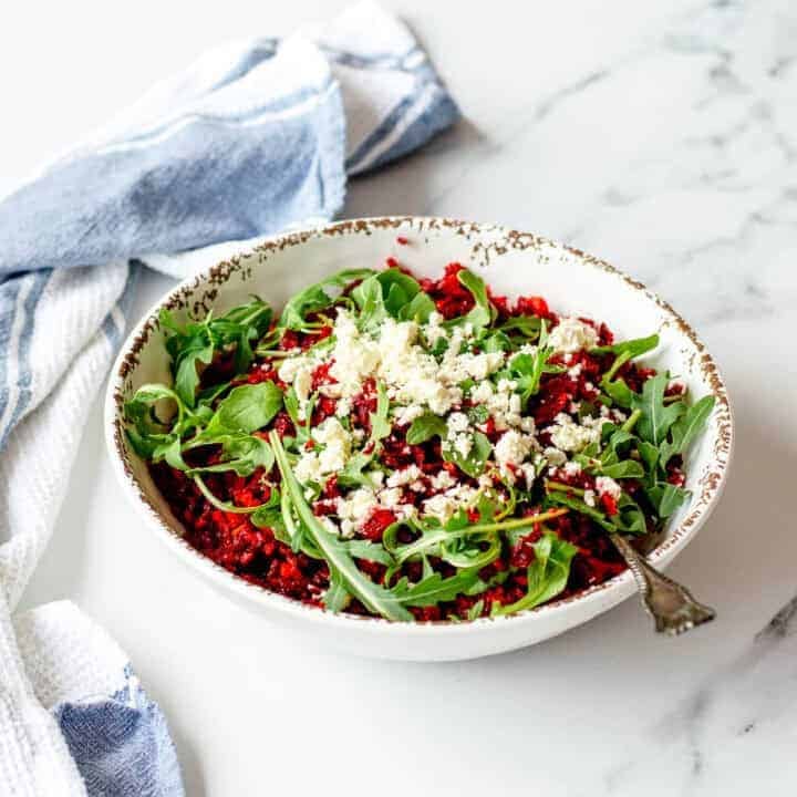 Beetroot and feta salad in a white bowl, sitting on a marble benchtop.