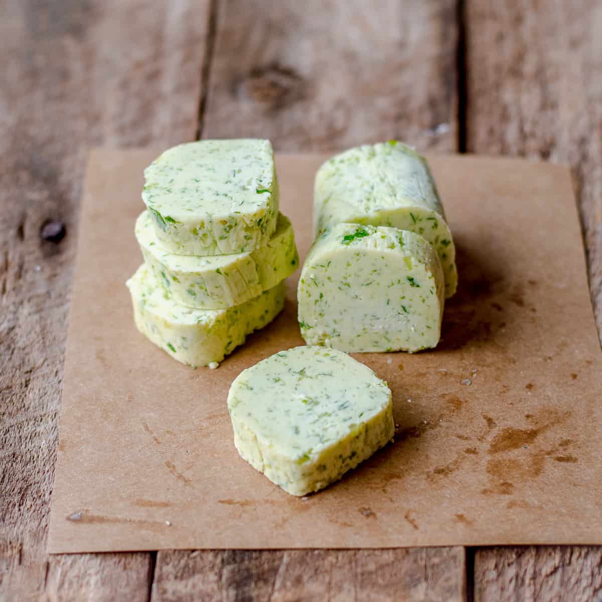 Homemade Garlic Parsley Butter cut into slices on brown paper