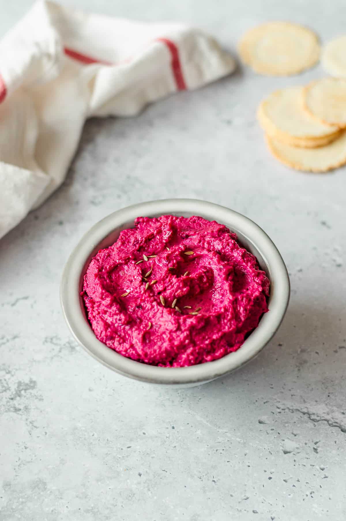 A grey bowl filled with bright pink beetroot hummus.