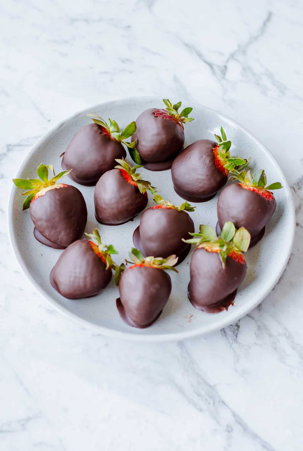 Chocolate dipped strawberries on a grey plate.