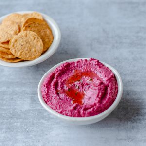 Fresh Roasted Beetroot Hummus in a white bowl with corn chips.