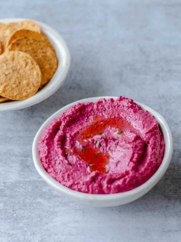 Fresh Roasted Beetroot Hummus in a white bowl with corn chips.