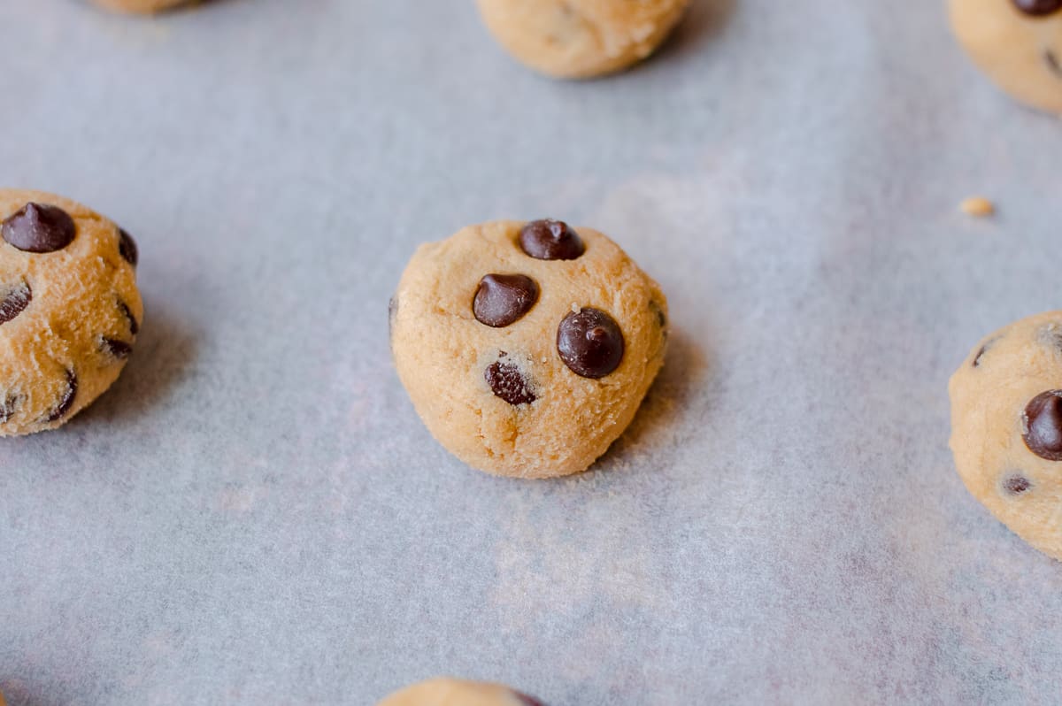 Raw chocolate chip cookie dough ball on baking sheet