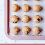 12 cookie dough balls on a rose gold baking tray