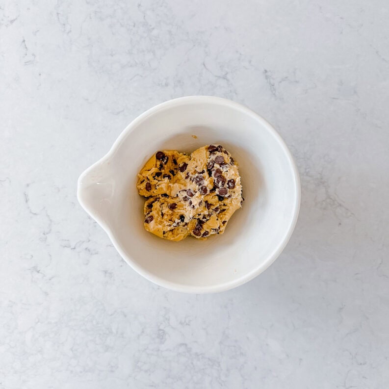 Chocolate chip cookie dough in a cream mixing bowl.