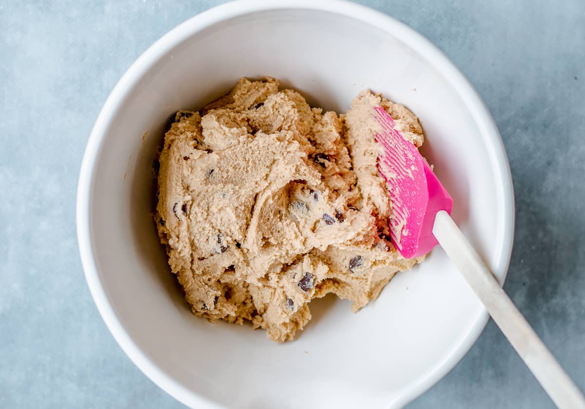 Raw Chocolate Chip Cookie Dough in white bowl with pink spatular.