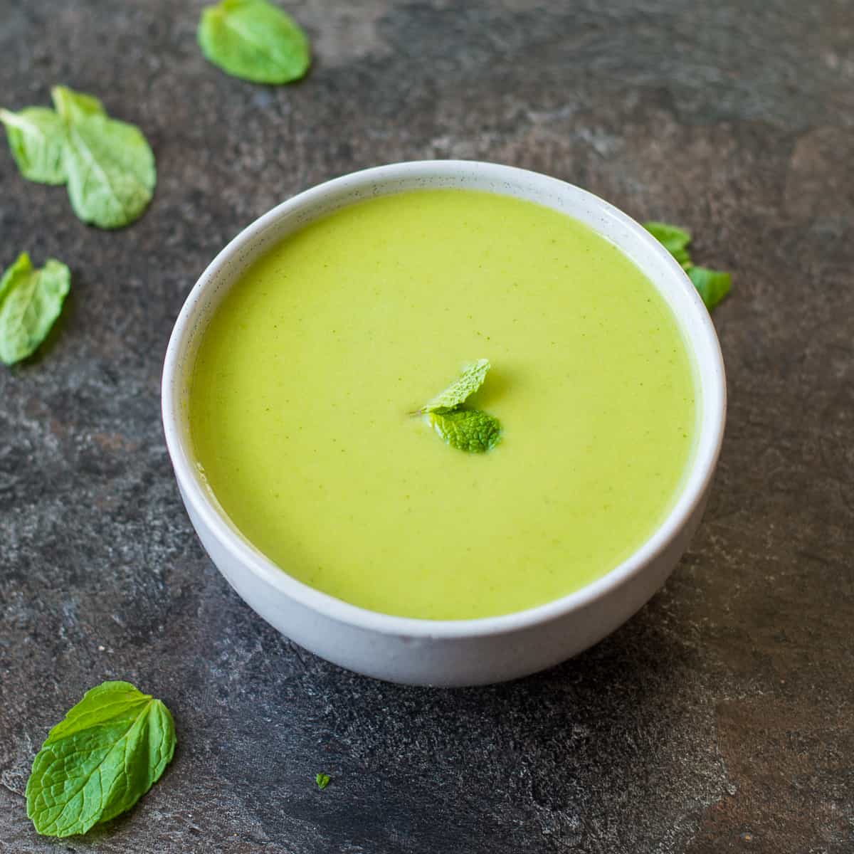 Pea and Mint Soup in grey bowl on dark background.