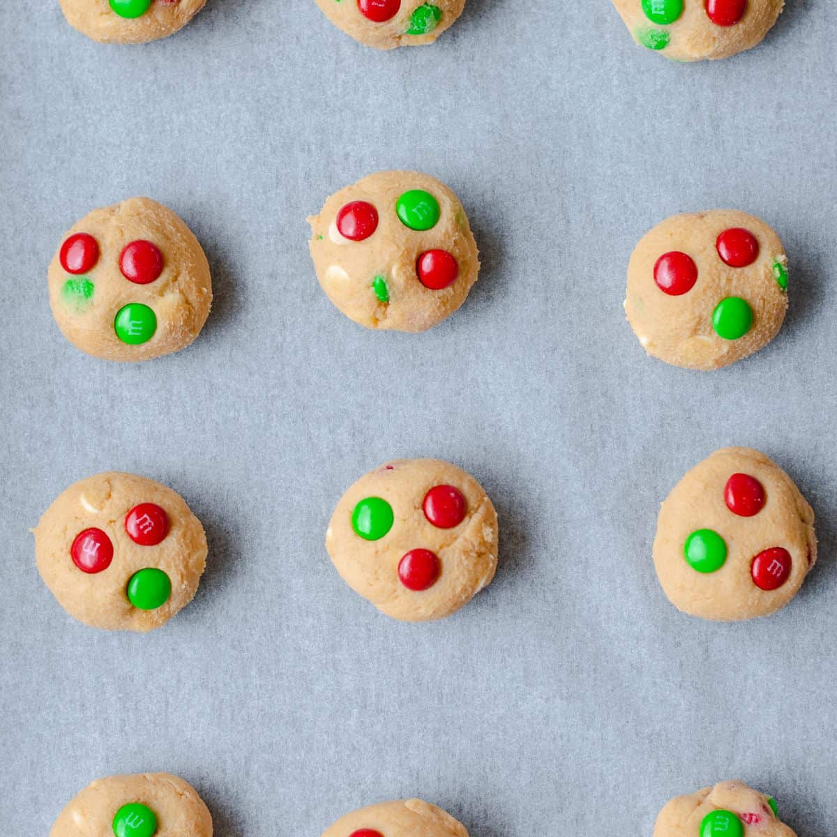 Raw M and M Cookie dough balls on a baking tray.