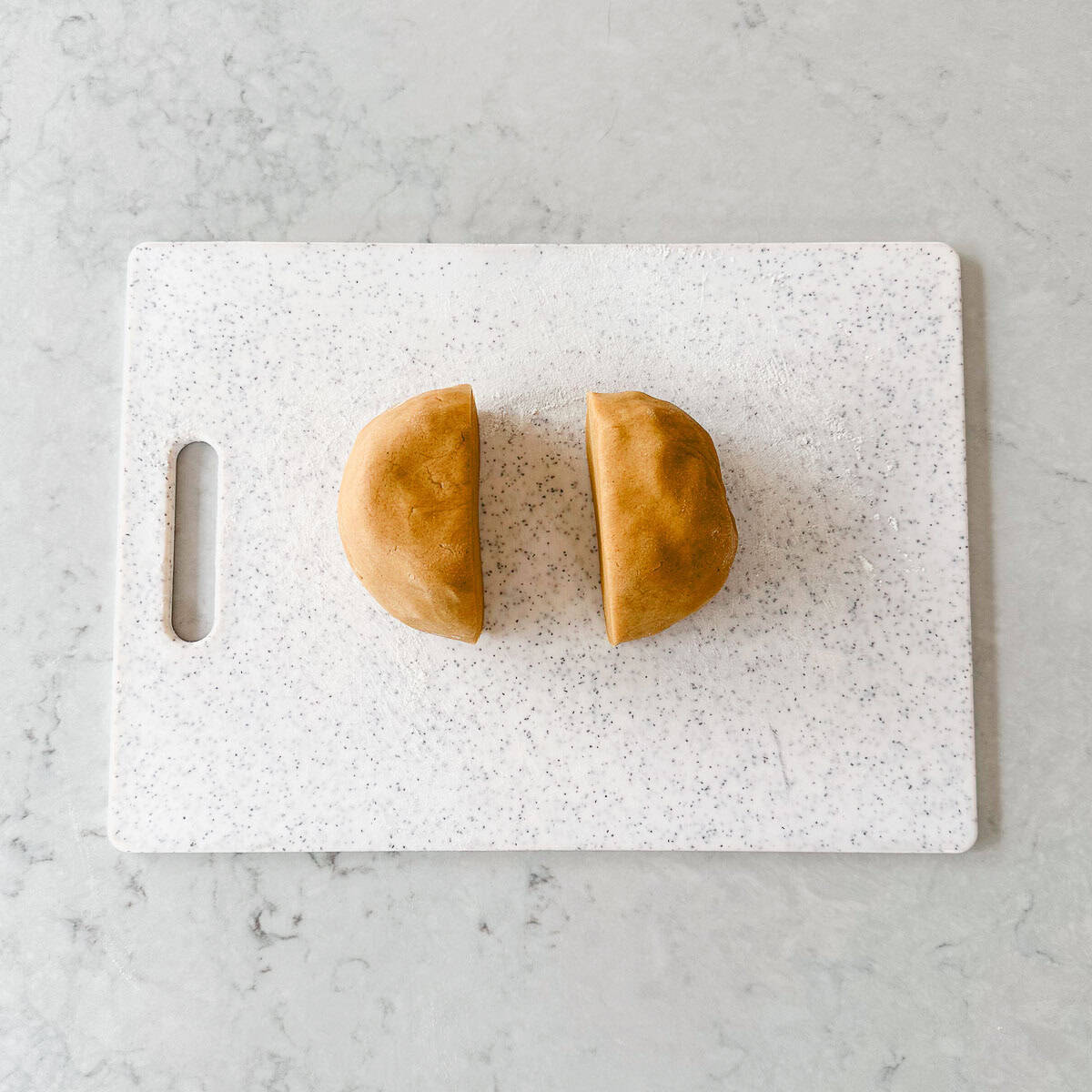 Two gingerbread halves on a white cutting board.