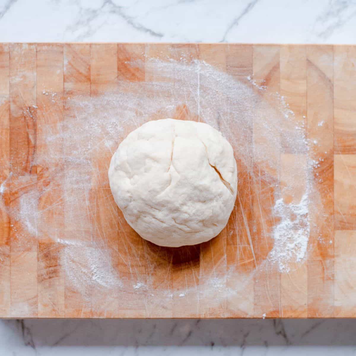 A ball of dough on a wooden board.