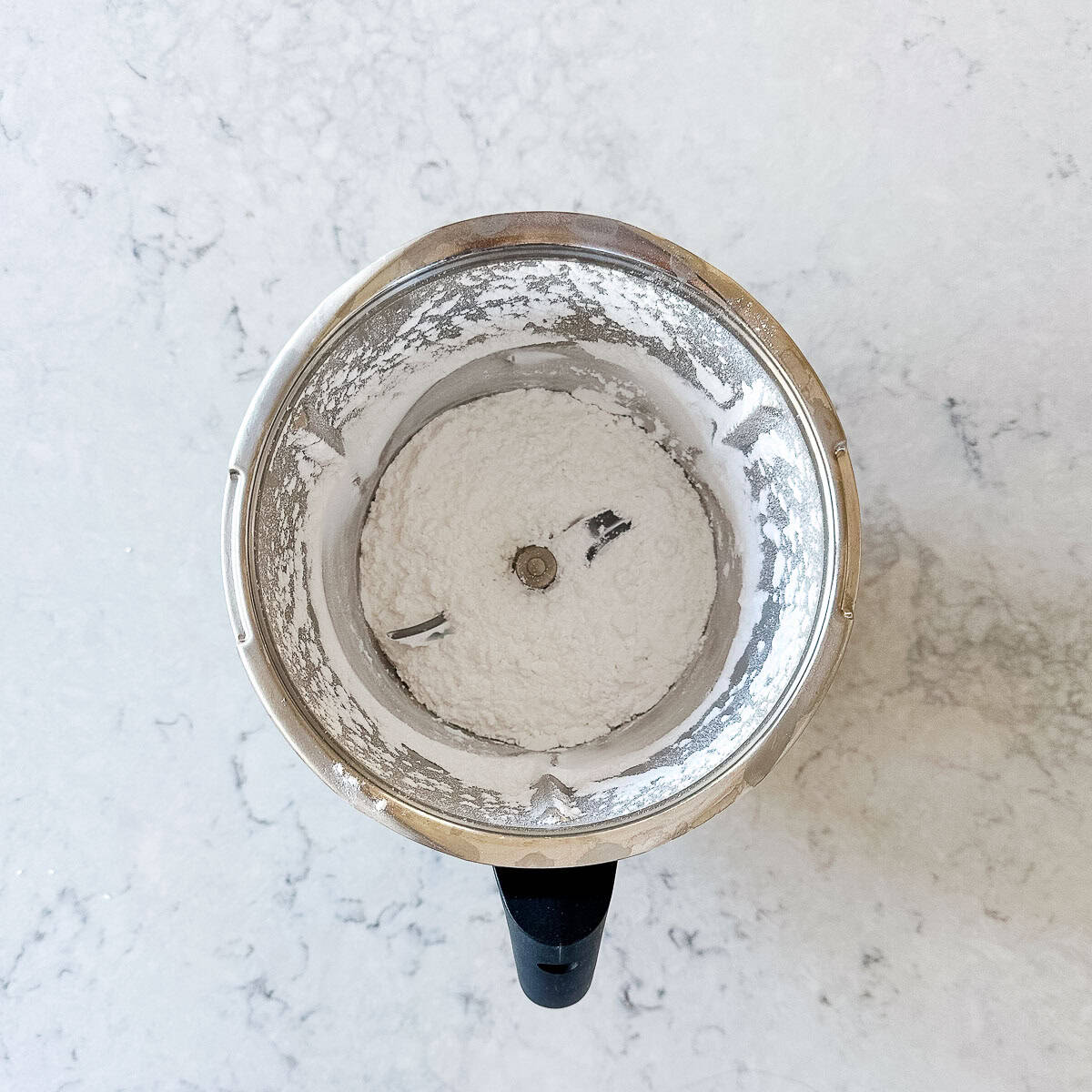 A Thermomix bowl filled with icing sugar.