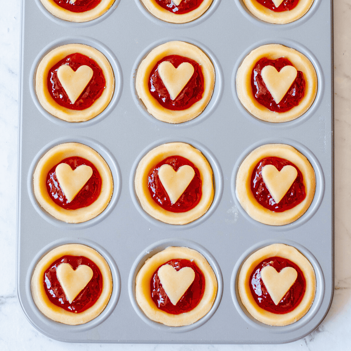 Jam Tarts with hearts in a muffin tin.
