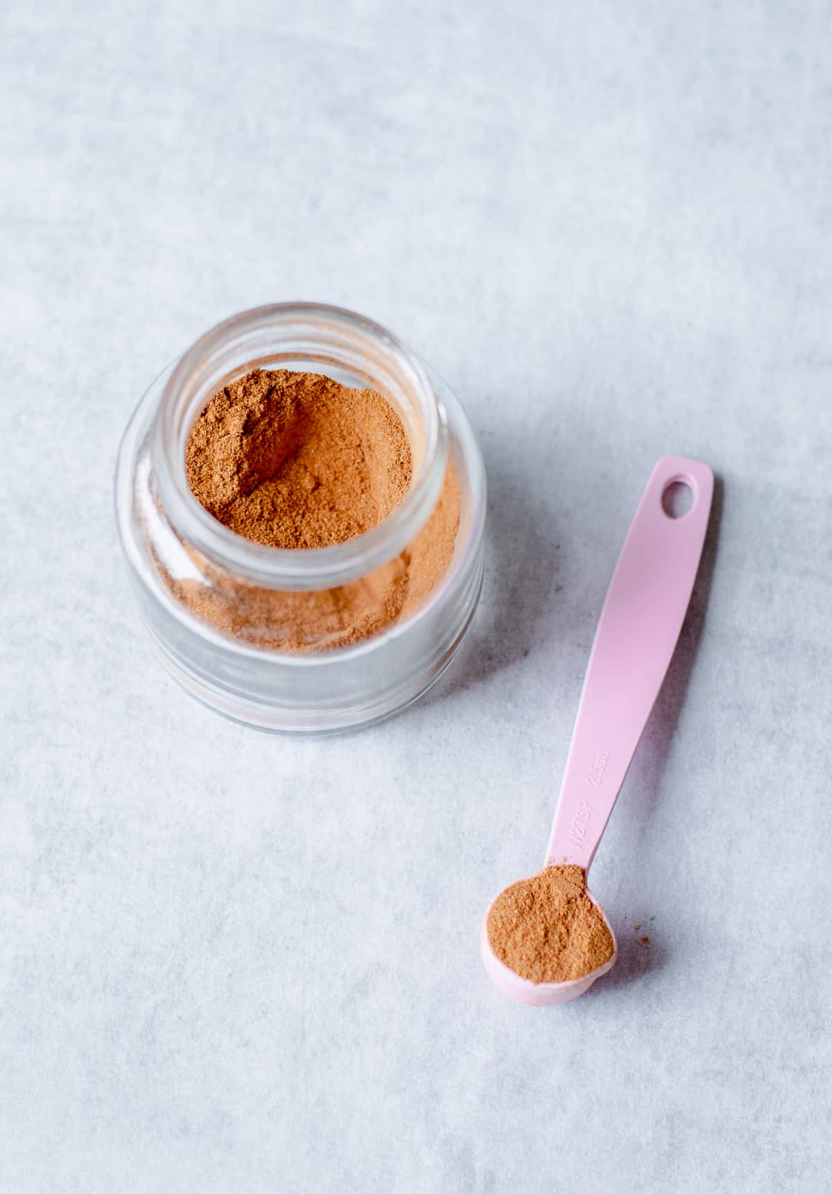 chai spice mix in a glass jar with pink spoon