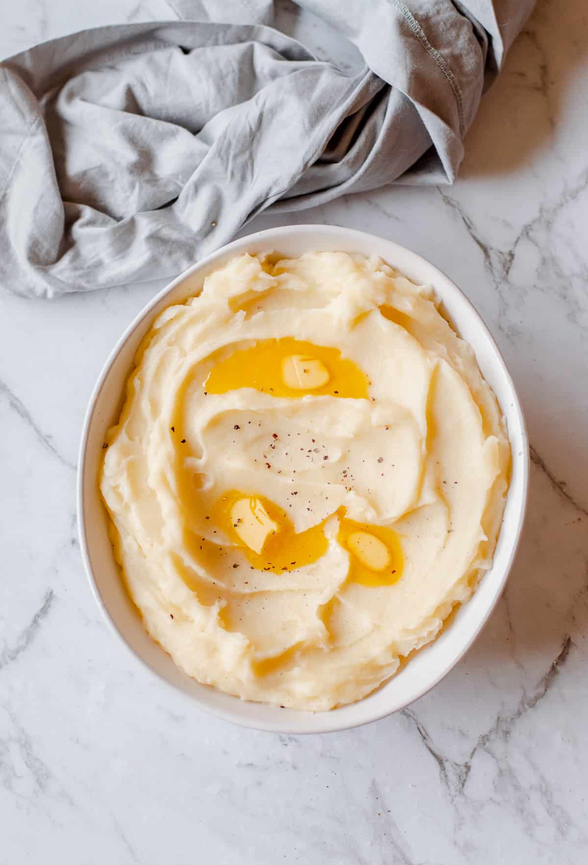 mashed potatoes in white bowl with melted butter on top