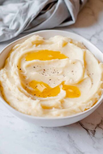 mashed potatoes in white bowl with melted butter on top
